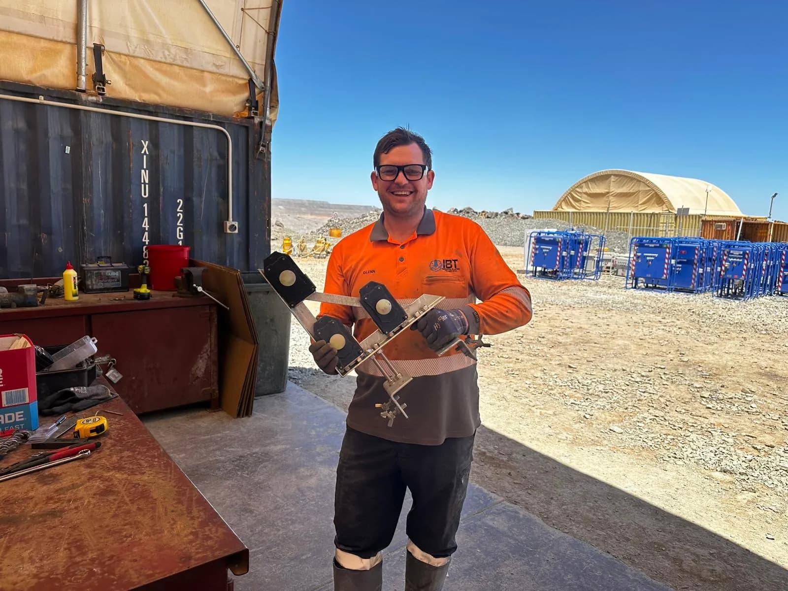 Glenn holding survey marker hardware outside the site workshop