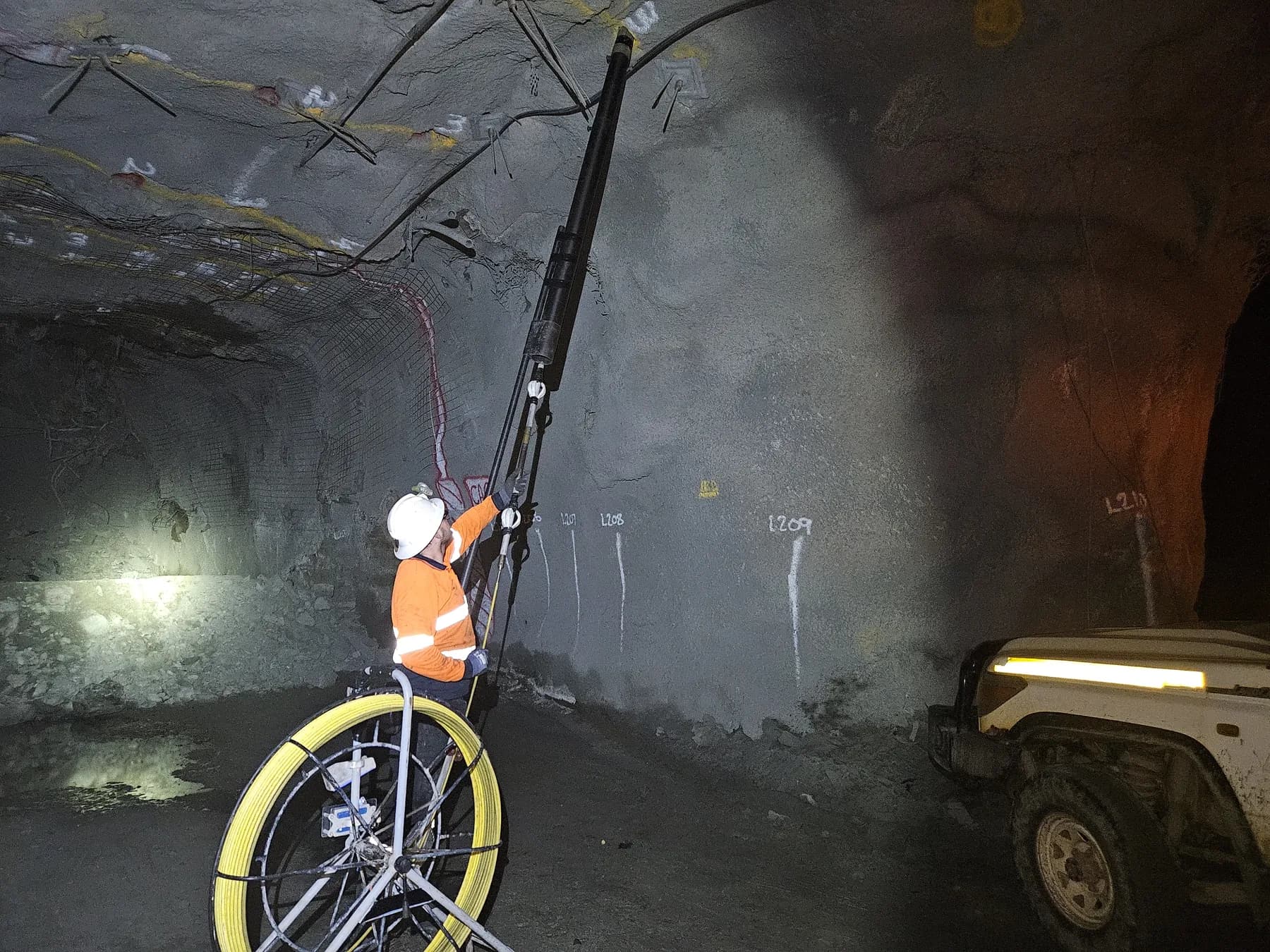 Surveyor at the foot of a drive wall pushing the gyro up a hole on the Feeder Pole, a survey ute parked alongside